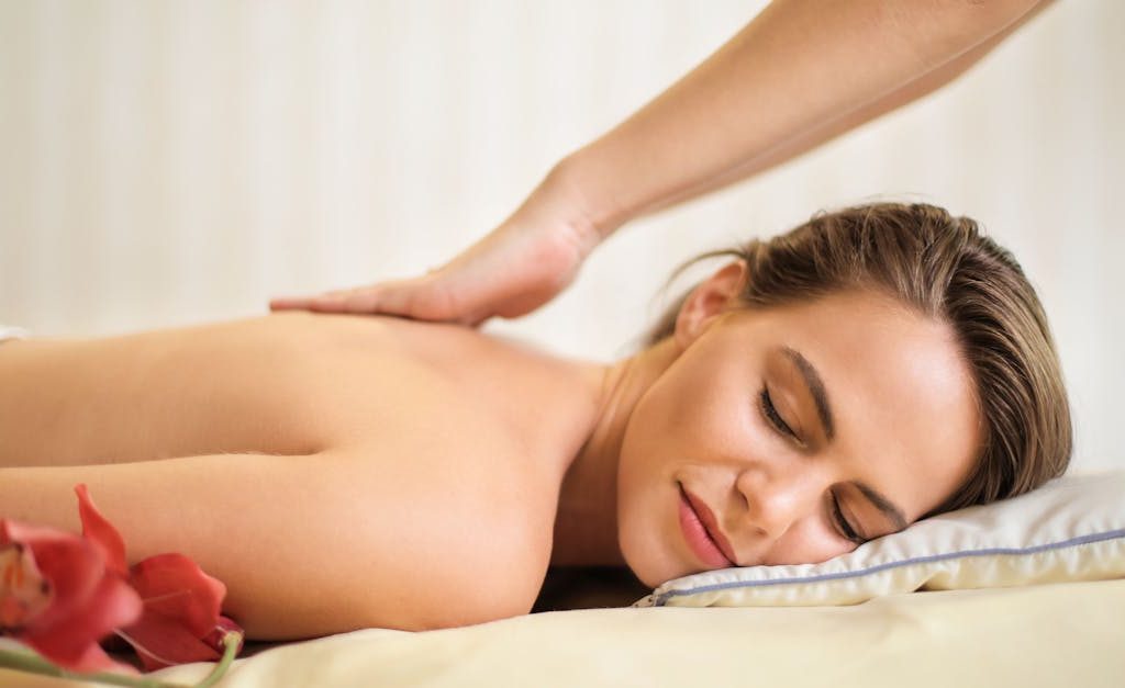 A serene spa scene featuring a woman receiving a therapeutic massage, surrounded by soothing elements.